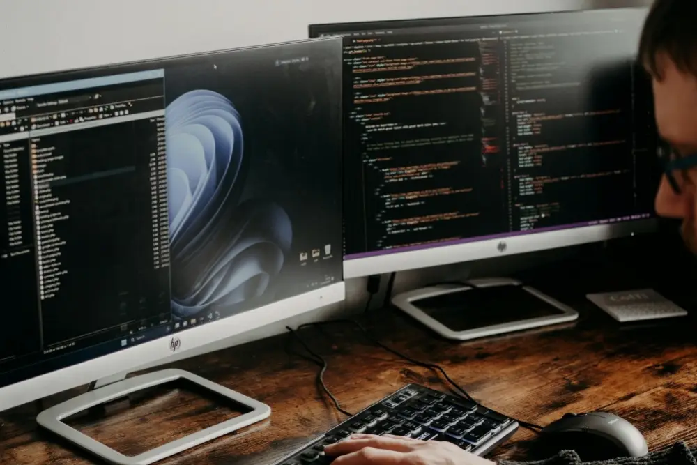 website developer coding a website on two monitors